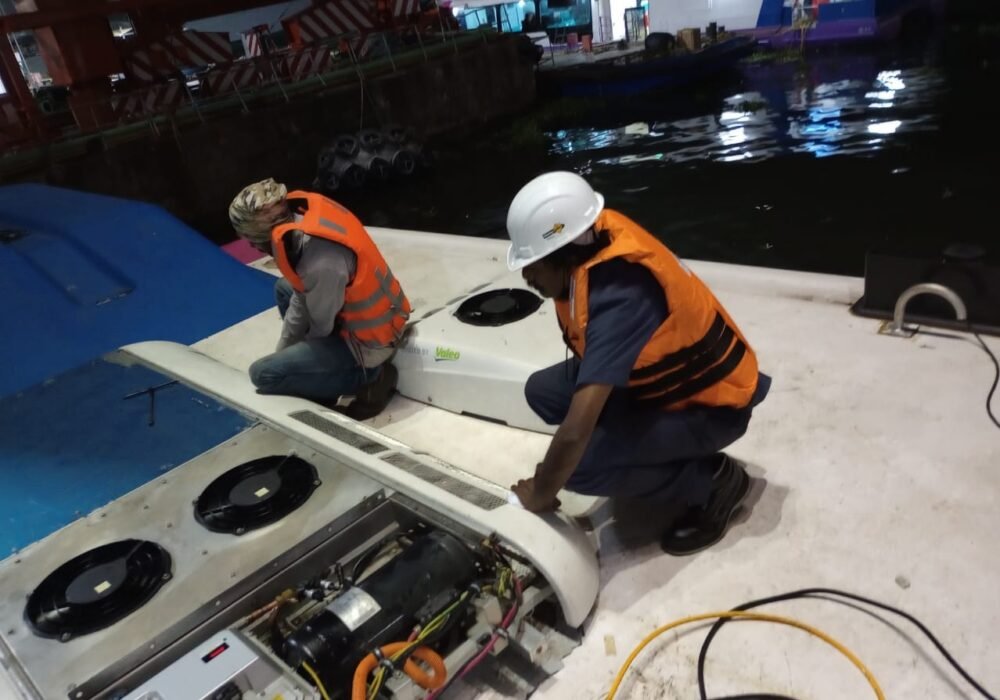 Technicians fitting a rooftop air conditioning unit on a vessel deck, Kochi